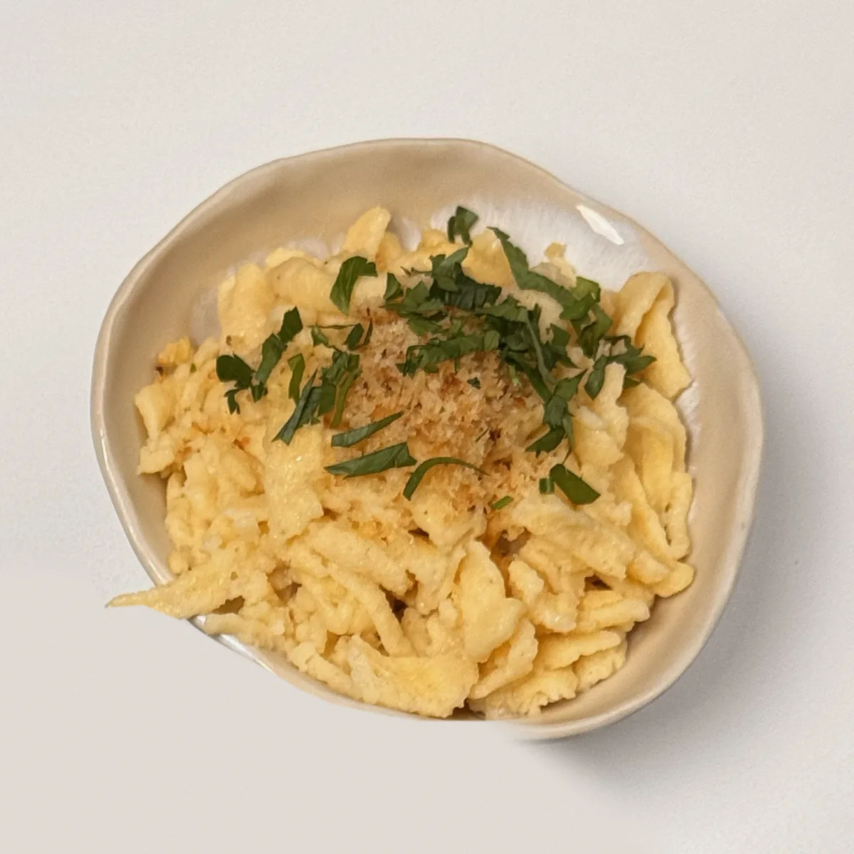 Geschmälzte Spätzle mit Butterbröseln und Kräutern im Keramikschälchen