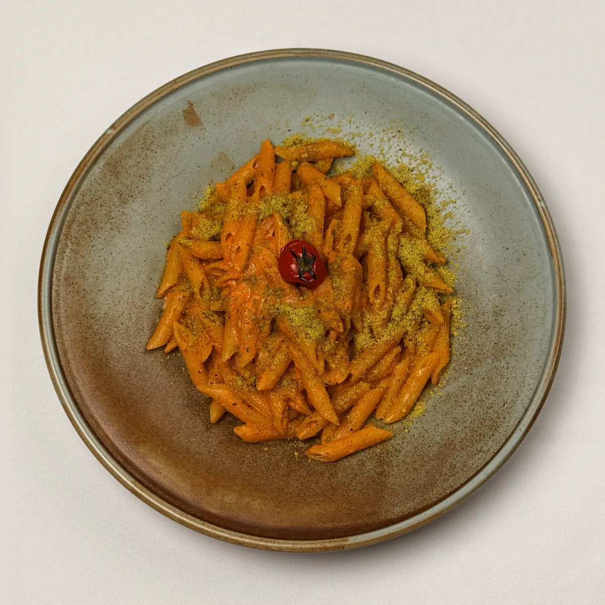 Penne all’Aurora in Tomaten-Sahnesoße mit Pistazienbröseln und einer Kirschtomate