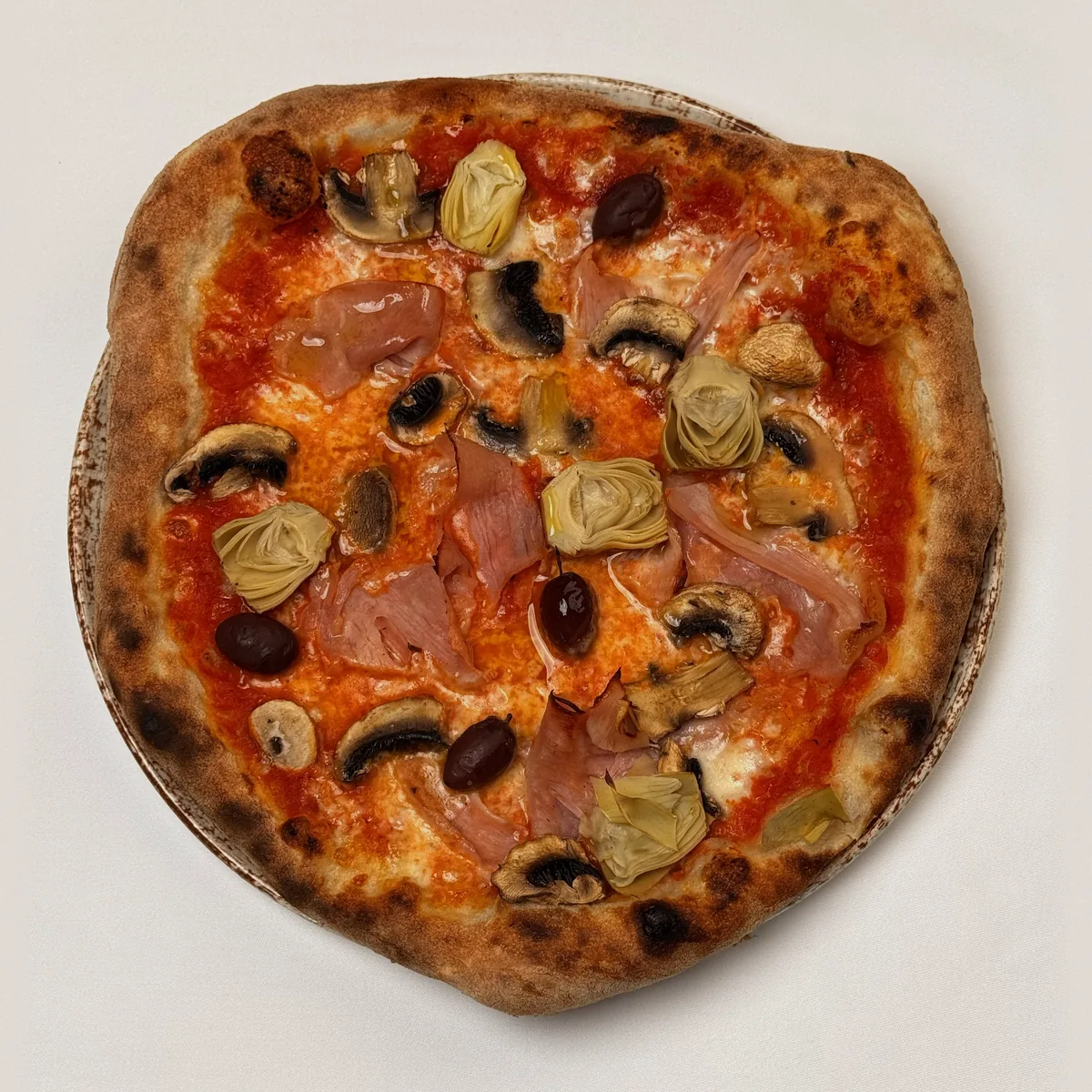 Pizza Capricciosa mit Schinken, Artischocken, Champignons und Oliven