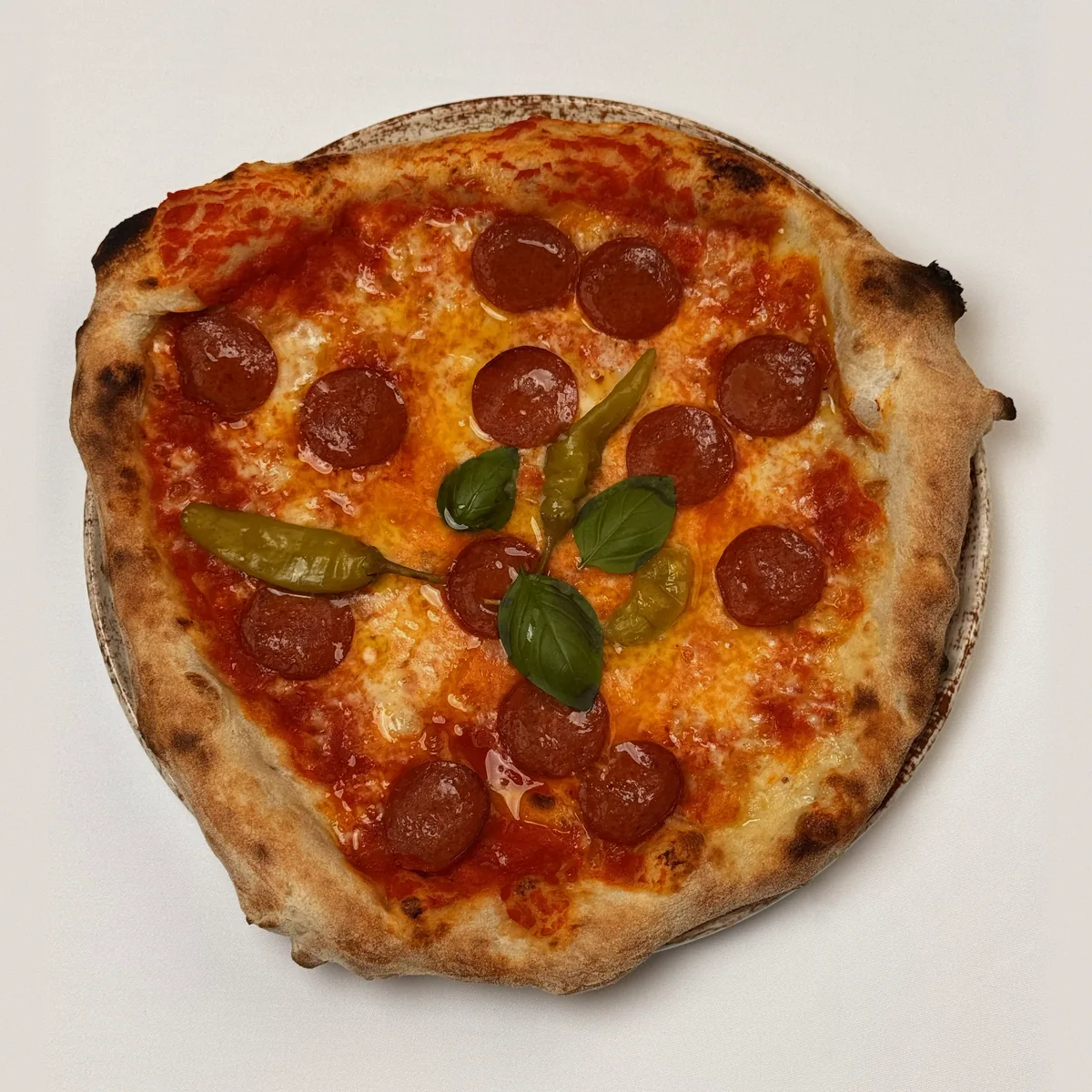 Pizza Diavola mit scharfer Salami, grünen Peperoni und Basilikum