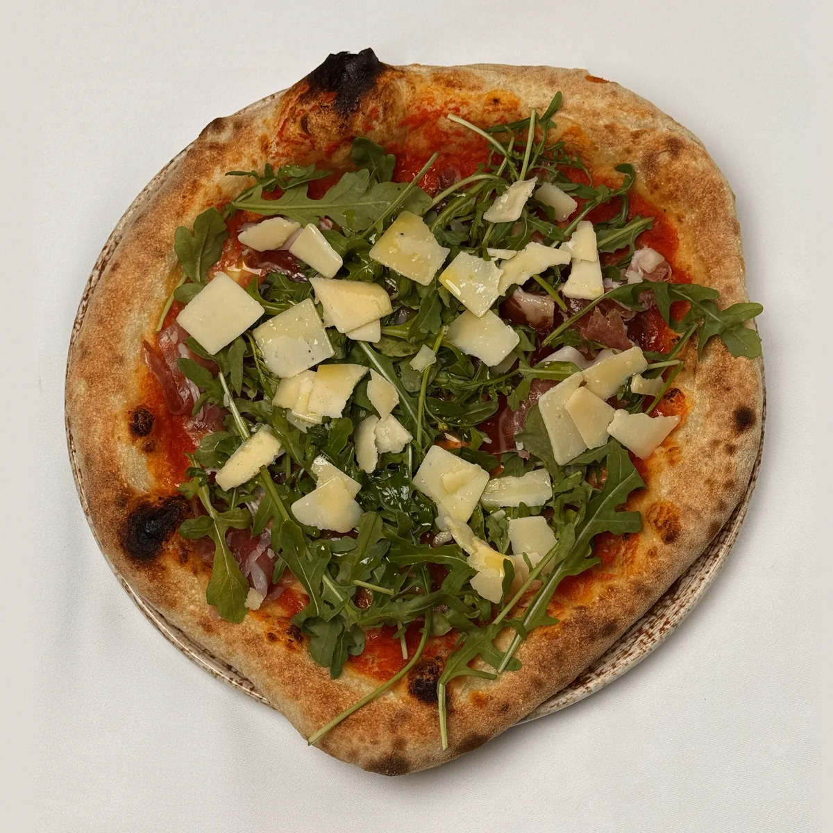 Pizza mit Rucola, Parmaschinken und gehobeltem Parmesan