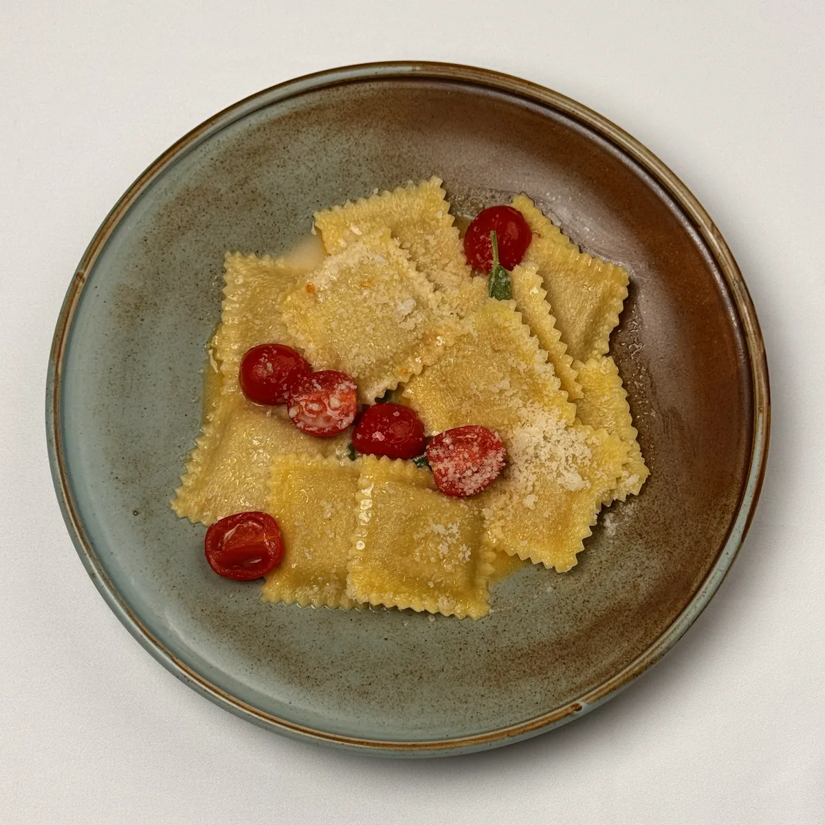 Eckige Ravioli in Salbeibutter mit geschmorten Kirschtomaten und geriebenem Parmesan