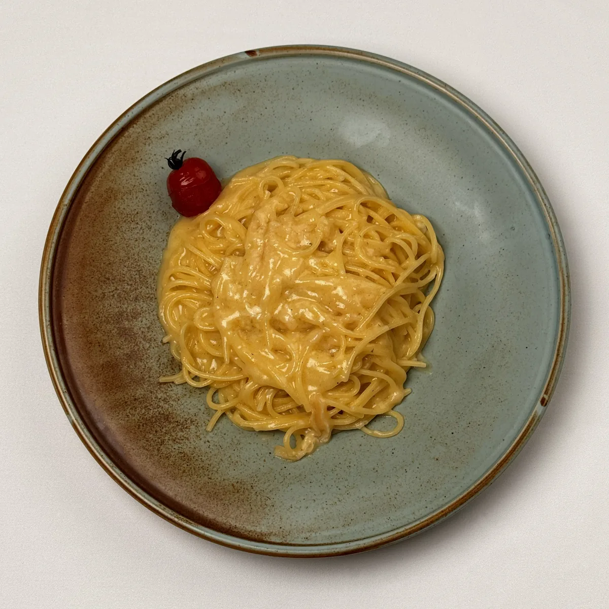 Spaghetti al Parmigiano in cremiger Parmesansoße mit einer Kirschtomate