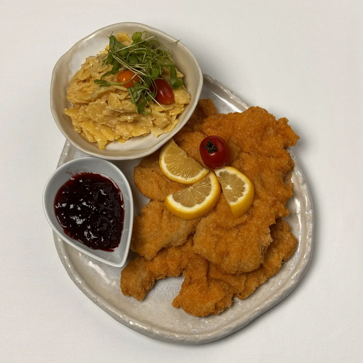 Wiener Schnitzele vom Kalb mit Zitronenscheiben, dazu Kartoffelsalat mit Kresse und Marmelade im Schälchen