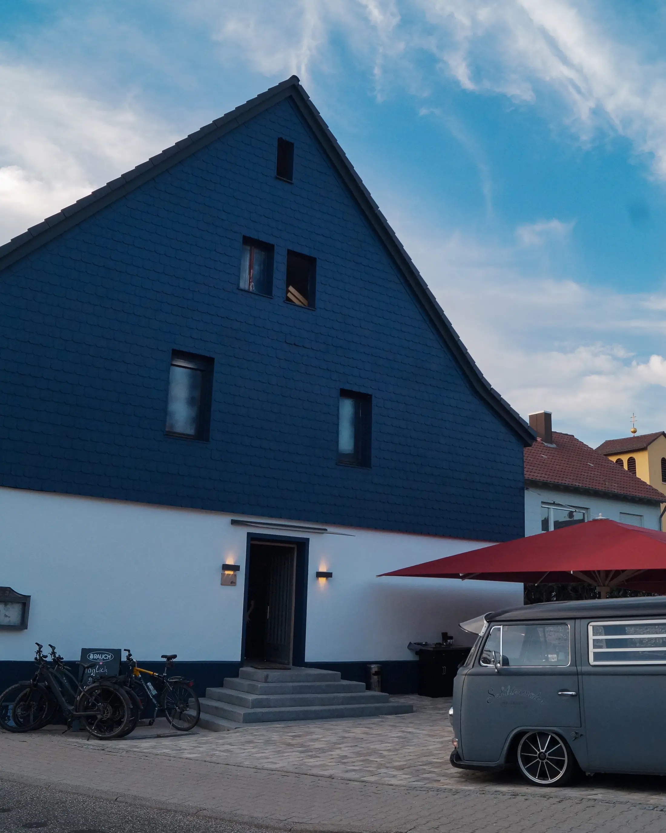 Der Landgasthof Engel in Hohenwart von der Straße aus, mit Sonnenschirmen und VW-Bulli
