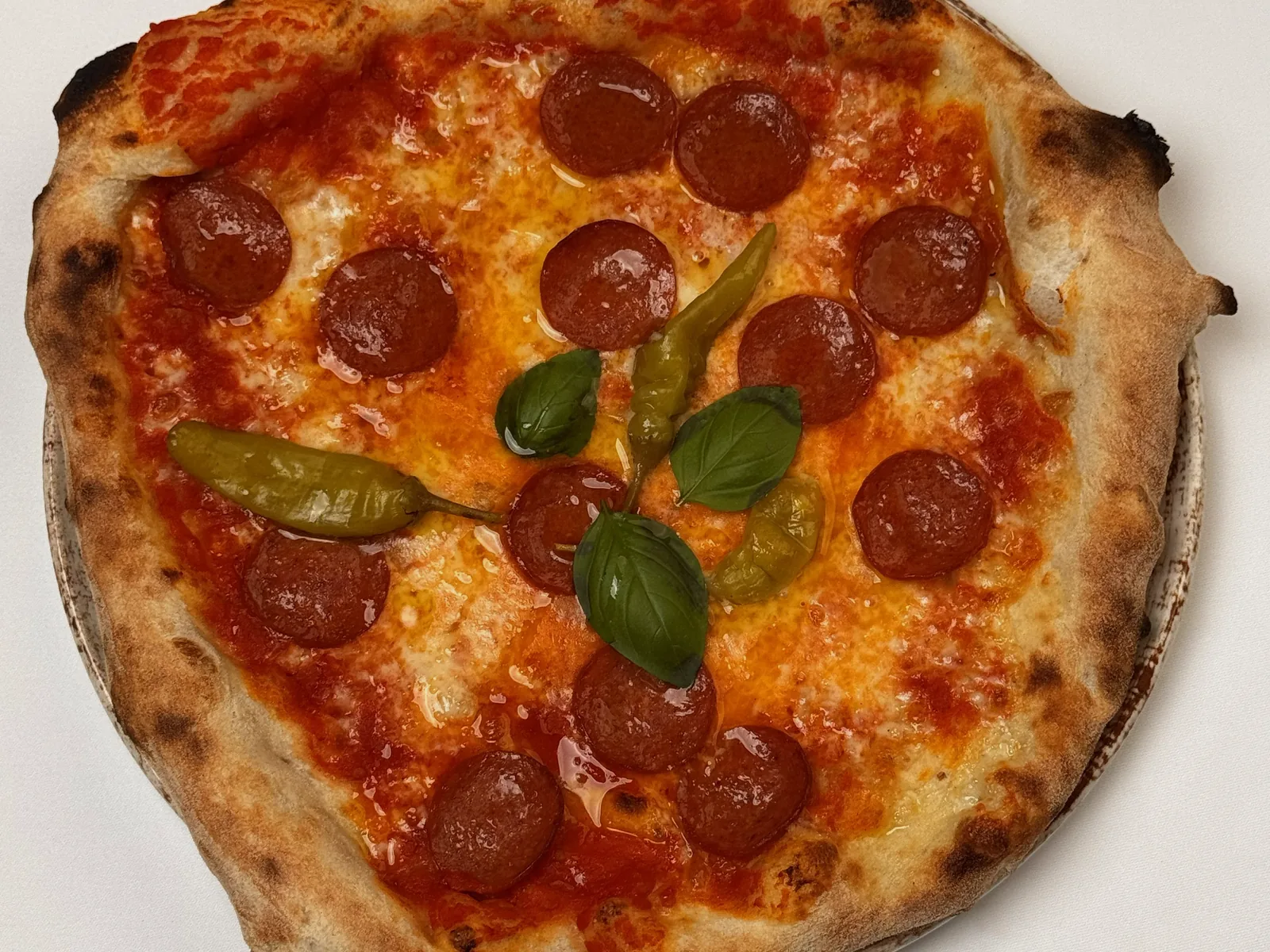 Pizza Diavola mit scharfer Salami, grünen Peperoni und Basilikum, von oben